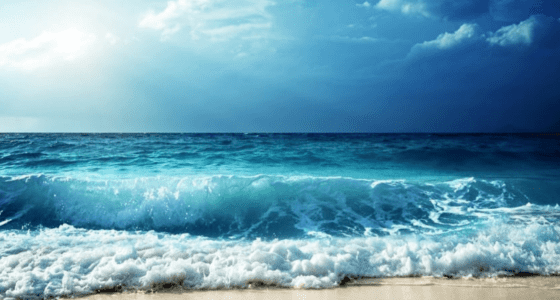 Seashore with waves and sunlight reflecting on water. .