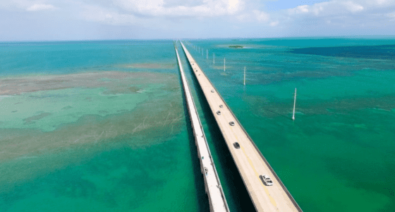 Aerial view of the Overseas Highway with cars surrounded by sea.