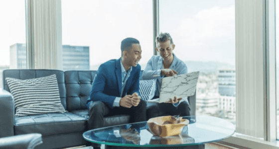 Two South Florida real state agents looking at a computer with a city background.