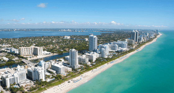 Aerial view of a sunny day at Miami Beach, with condos and hotels lined up by the beach