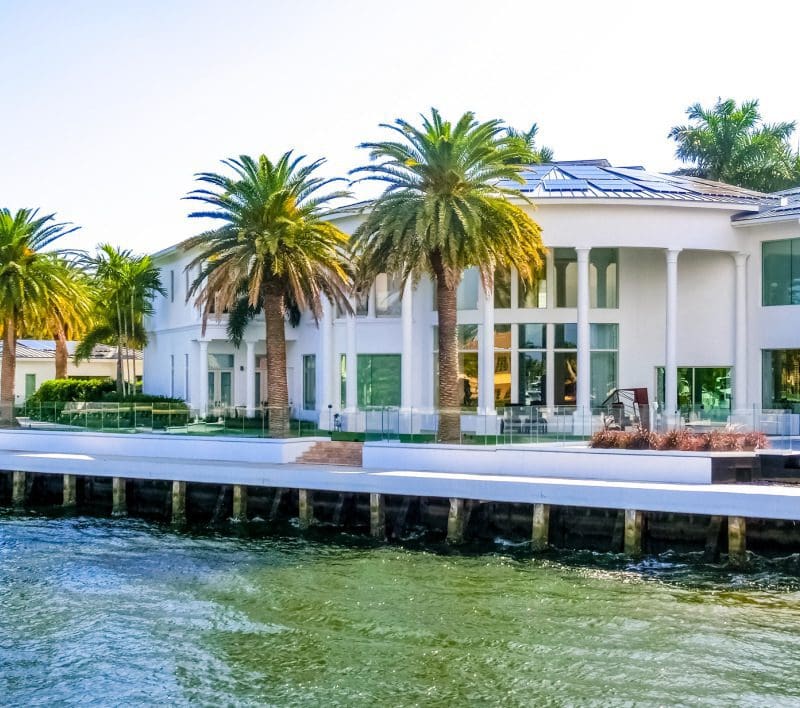 waterfront mansion with palm trees