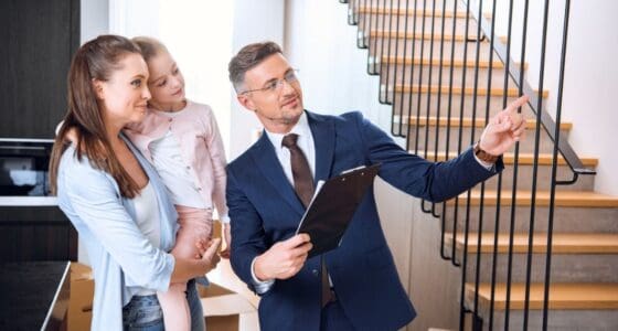 Handsome broker showing something to woman holding in arms cute daughter — Photo